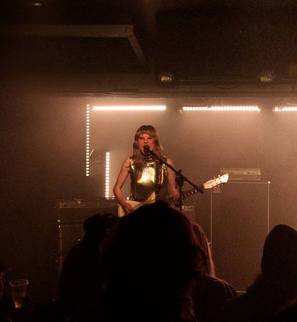 Photo of the Gussie from the band Earth Tongue holding a guitar and shouting into the microphone