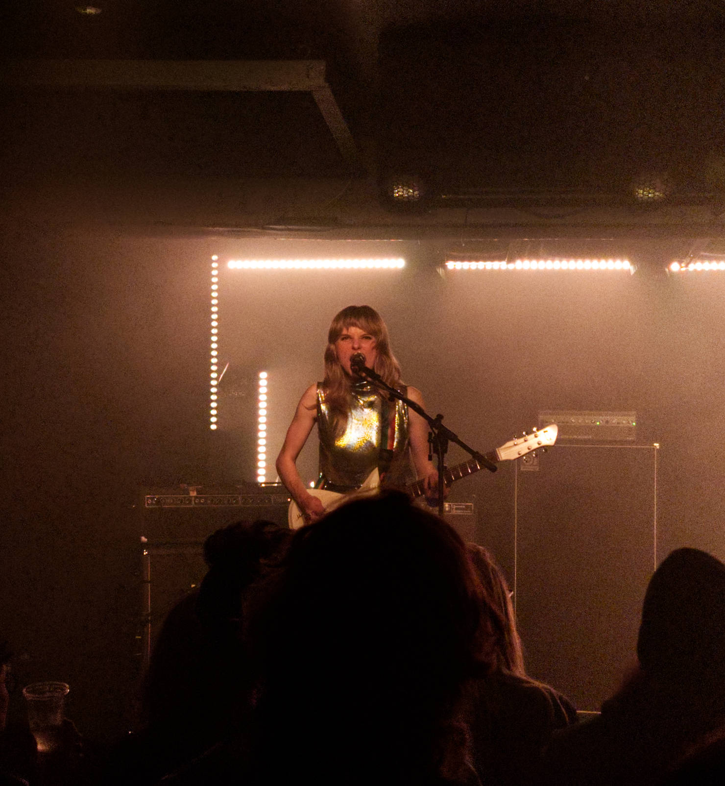 Photo of the Gussie from the band Earth Tongue holding a guitar and shouting into the microphone